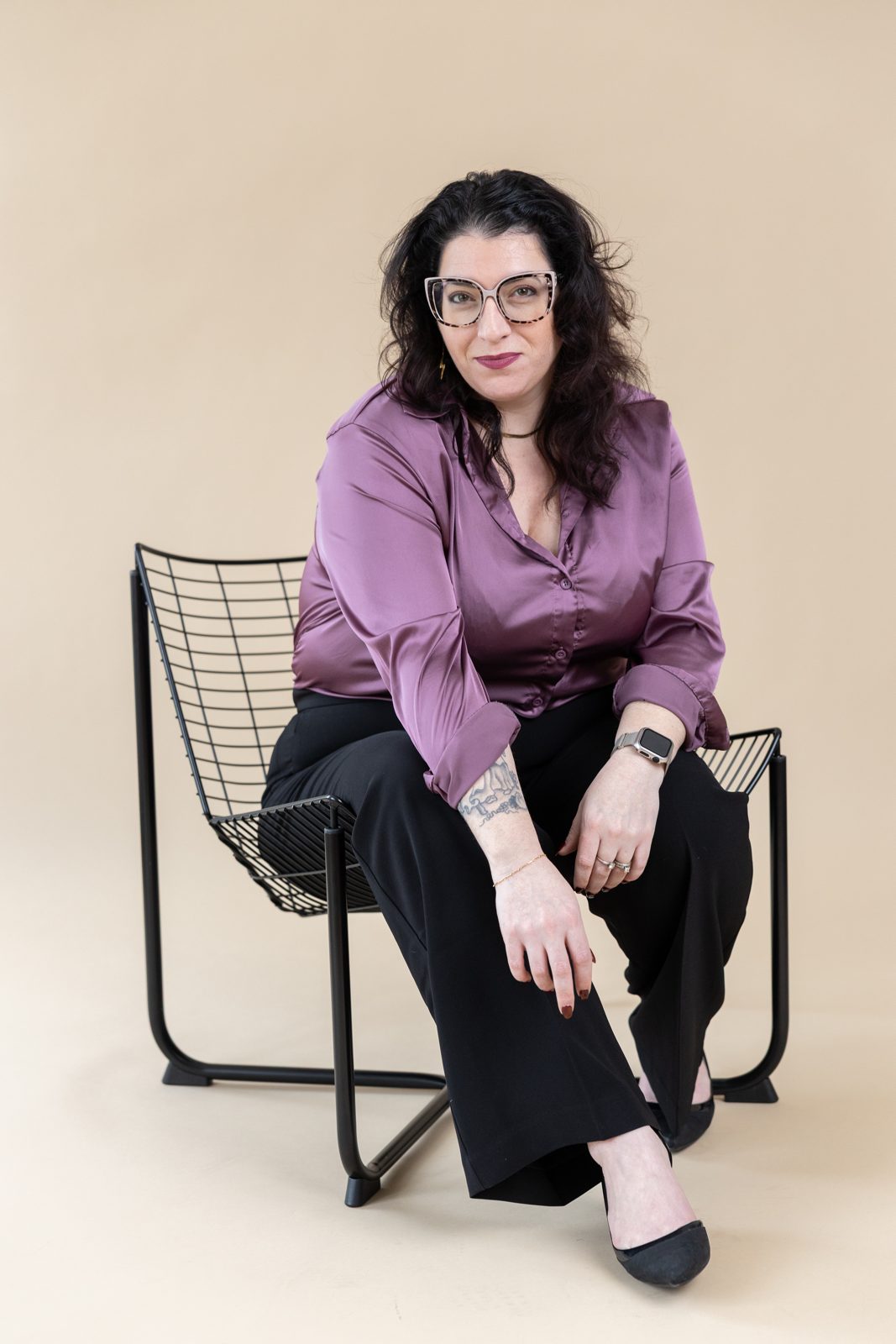 Lindsay Mastro seated on a black wire chair, leaning forward